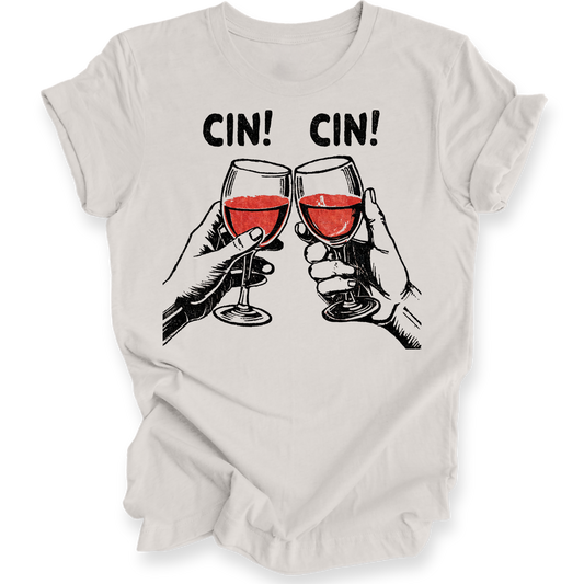 A light beige crewneck t-shirt with a graphic print of two hands clinking glasses of red wine under the text 'CIN! CIN!'.