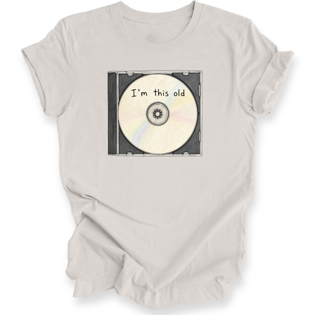 A light beige crewneck t-shirt with a graphic of a CD case containing a CD that reads 'I'm this old' in black text.