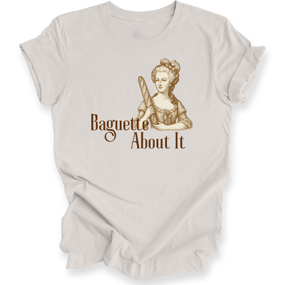 Beige t-shirt with a graphic of a woman holding a baguette and text 'Baguette About It' on a white background