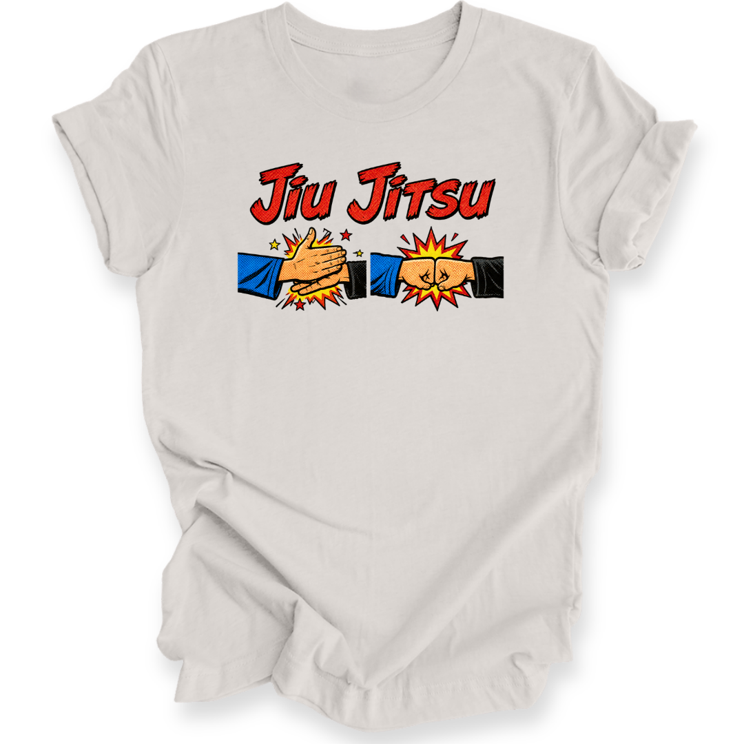 A light gray short-sleeve t-shirt with a 'Jiu Jitsu' graphic on the chest, featuring two cartoon hands in blue and black sleeves clashing with yellow stars and an explosion effect.
