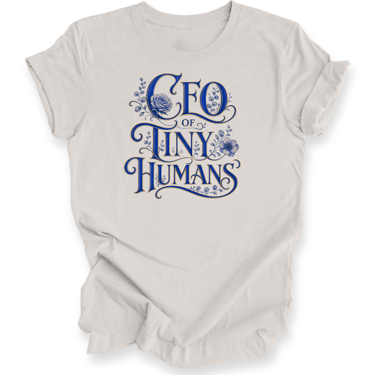 A light beige crewneck t-shirt with a blue graphic text print reading 'CEO OF TINY HUMANS' decorated with floral illustrations, shown on a plain white background.
