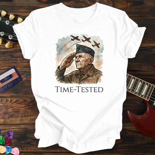 White t-shirt with a graphic of a man saluting and the text 'Time-Tested' on a wooden background with a guitar and cassette tape.