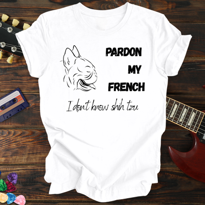 White t-shirt with graphic and text on a wooden surface with a guitar and cassette tape.