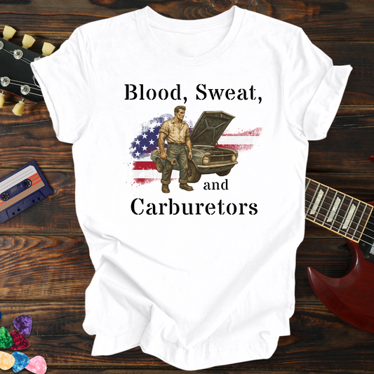 White t-shirt with graphic design of a man working on a car, American flag, and text 'Blood, Sweat, and Carburetors' on a wooden surface with a guitar and cassette tape.