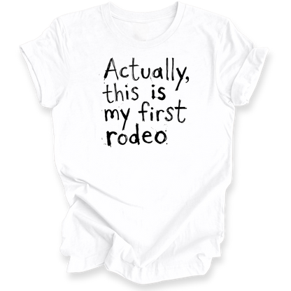 A white short-sleeve t-shirt with black hand-drawn text reading 'Actually, this is my first rodeo' on the front, displayed against a clean white background.