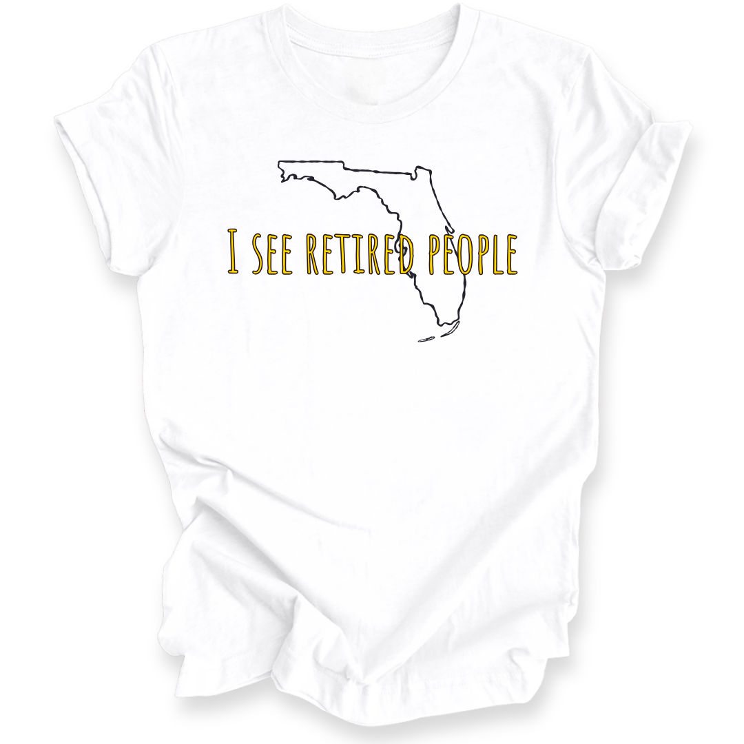 A white short-sleeve crewneck t-shirt with a graphic of the state outline of Florida in black, with the text 'I SEE RETIRED PEOPLE' written across it in a textured gold font.